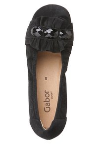 Svart mocka platt sko med en rynkad rem och dekorativa glansiga svarta accenter. Insidan visar varumärket "Gabor sport" i ljus färg.