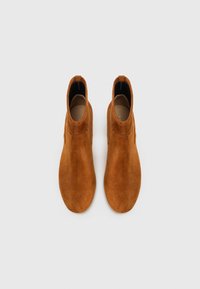 Suède enkelboots in een warme tan kleur, met een gladde textuur, slanke vorm en een minimalistisch ontwerp zonder zichtbare hardware.
