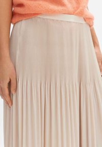 Plissé midi rok van zachte beige stof, met een soepele tailleband en verticale plooien, die een vloeiende textuur creëren.