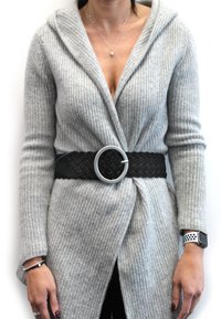 Helle graue Strickjacke mit Kapuze, langen Ärmeln und asymmetrischer Front, die in der Taille mit einem schwarzen geflochtenen Gürtel und einer silbernen Schnalle gerafft ist.