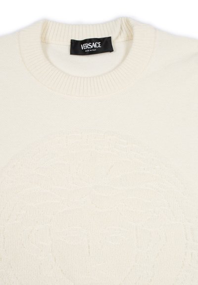 Maglione a maglia crema con collo girocollo a coste e design in rilievo della testa di Medusa, con etichetta nera Versace con la scritta "Made in Italy".