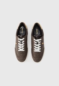 Καφέ αθλητικά παπούτσια με μοτίβο, λευκά κορδόνια, μπεζ λεπτομέρειες και λογότυπο. Μαλακό ύφασμα στην επιφάνεια, στρογγυλεμένη μύτη και μαλακό, επενδεδυμένο εσωτερικό.