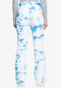Snowboard pants in a white and light blue cloud pattern. Features a zippered pocket on the back and a tailored fit for mobility.