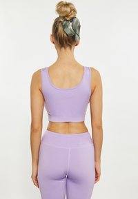 Sutien sport lavandă cu un design ajustat și bretele late, asociat cu colanți lavandă asortați. Țesătură netedă cu accente fără cusături.