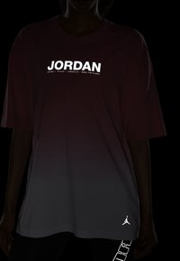 Přetahující tričko v maroon a šedém gradientu s logem "JORDAN" v reflexní bílé. Obsahuje krátké rukávy a minimalistický design.