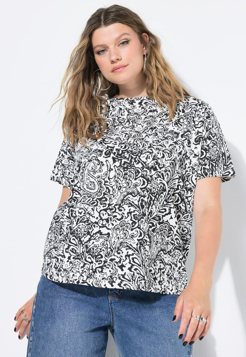 Černobílý top s paisley vzorem, krátký rukáv, volný střih, vyrobený z látky s jemnou texturou. Kombinován s modrými džíny.