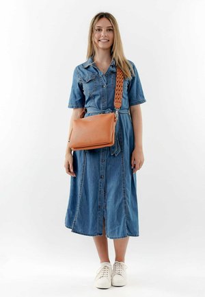Denim dress with short sleeves, button-down front and belted waist; orange leather bag with textured surface and woven strap; white sneakers.