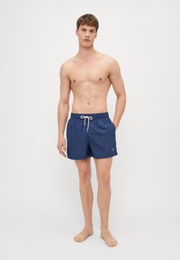 Marineblaue Badehosen mit einem Kordelzugbund, aus leichtem Material, mit einem gestickten Logo auf der linken Seite.