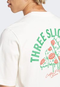 Witte katoen T-shirt met een kleurrijk grafisch ontwerp van pizzapunten, met groene tekst "DRIE SCHILDEREN" op de achterkant.