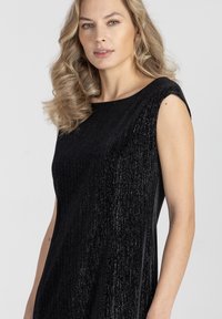 Czarna sukienka o prążkowanej fakturze, z krótkimi rękawami i szerokim dekoltem. Materiał ma delikatny połysk, który dodaje wizualnego zainteresowania.