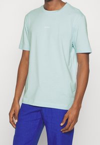 Ljusblå bomullströja med rund halsringning och korta ärmar. Har en liten vit "BOSS"-logotyp på bröstet. Avslappnad passform.