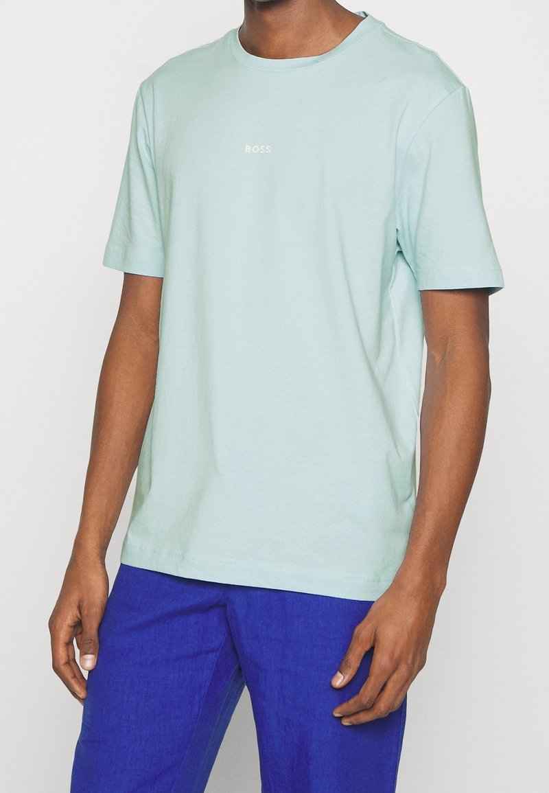 Ljusblå bomullströja med rund halsringning och korta ärmar. Har en liten vit "BOSS"-logotyp på bröstet. Avslappnad passform.