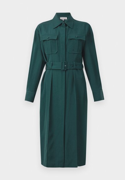 Robe chemise ceinture verte foncée avec manches longues, fermeture à boutons et deux poches poitrine, conçue avec une silhouette droite et des plis.