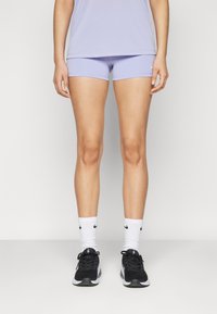 Lilac athletic shorts with a smooth texture, paired with black sneakers and white Nike socks featuring a logo.