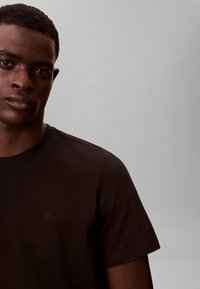 Zwart katoenen T-shirt met een ronde hals en korte mouwen. Voorzien van een subtiel CK-logo op de borst. Gladde textuur en getailleerd ontwerp.