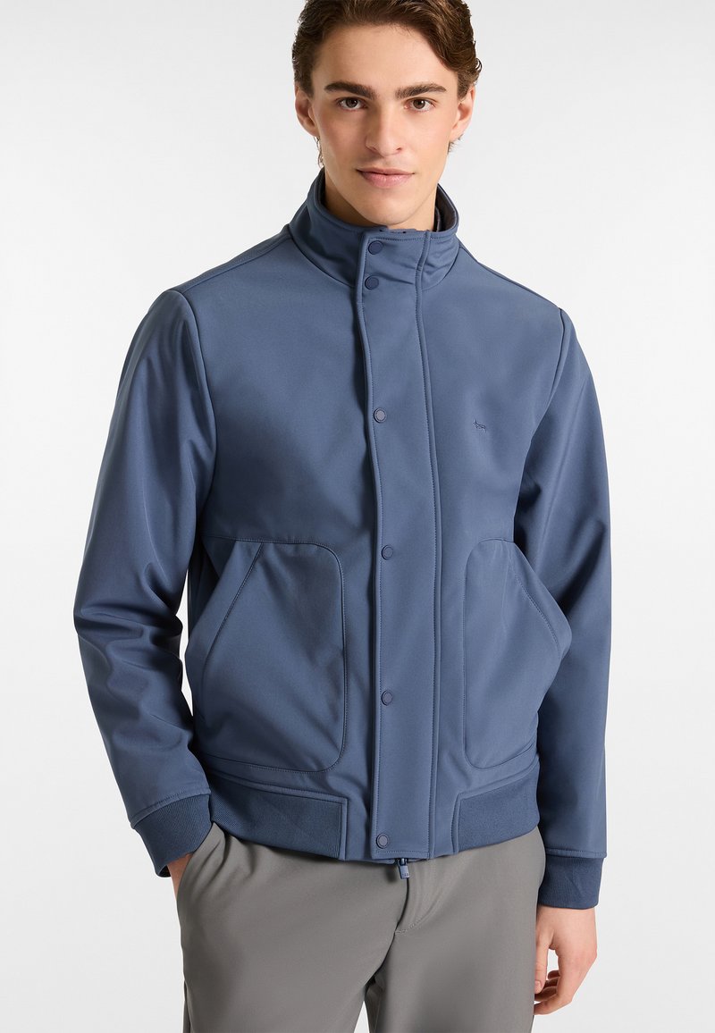 Giacca soft-shell blu con colletto alto, bottoni a scatto e due tasche laterali. Presenta una texture liscia e un design aderente.
