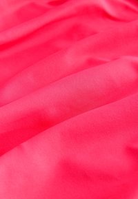 Napsütötte rózsaszín anyag sima textúrával, amely finom redőkkel és egységes mintázattal rendelkezik. A fény egyenletesen tükröződik a felületen.