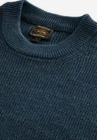 Ciemnoniebieski sweter prążkowany o grubej dzianinowej strukturze, z okrągłym dekoltem i metką z napisem "Premium Grade 1982".