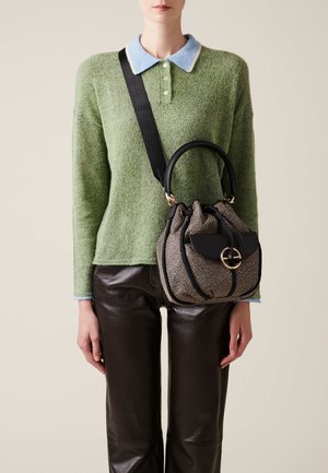 Brown leather pants, green textured sweater with a light blue collar, and a black and gold patterned handbag with a rounded handle.