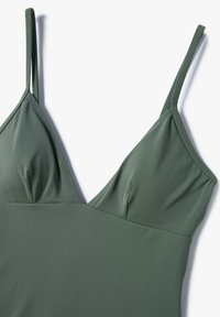 Groene zwempak met verstelbare dunne bandjes en een driehoekig cupontwerp. Gemaakt van gladde, lichtgewicht stof met een matte afwerking.