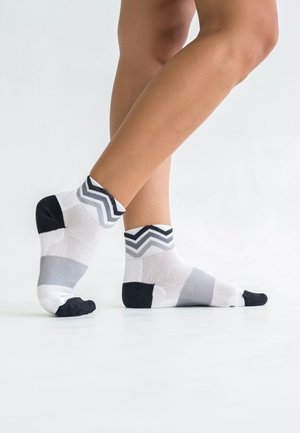 Knee-high socks in black, white, and grey with a chevron pattern. Made from soft, stretchy material with a textured footbed and solid toe.