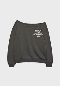 Sweat-shirt gris foncé à épaules dénudées avec texte blanc "APPRÉCIEZ LE VOYAGE PAS LA DESTINATION" sur le côté supérieur gauche.