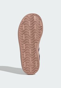 Suola di scarpa in gomma con texture ondulata, colore rosa chiaro e logo del brand in rilievo. Il design include scanalature per la trazione.