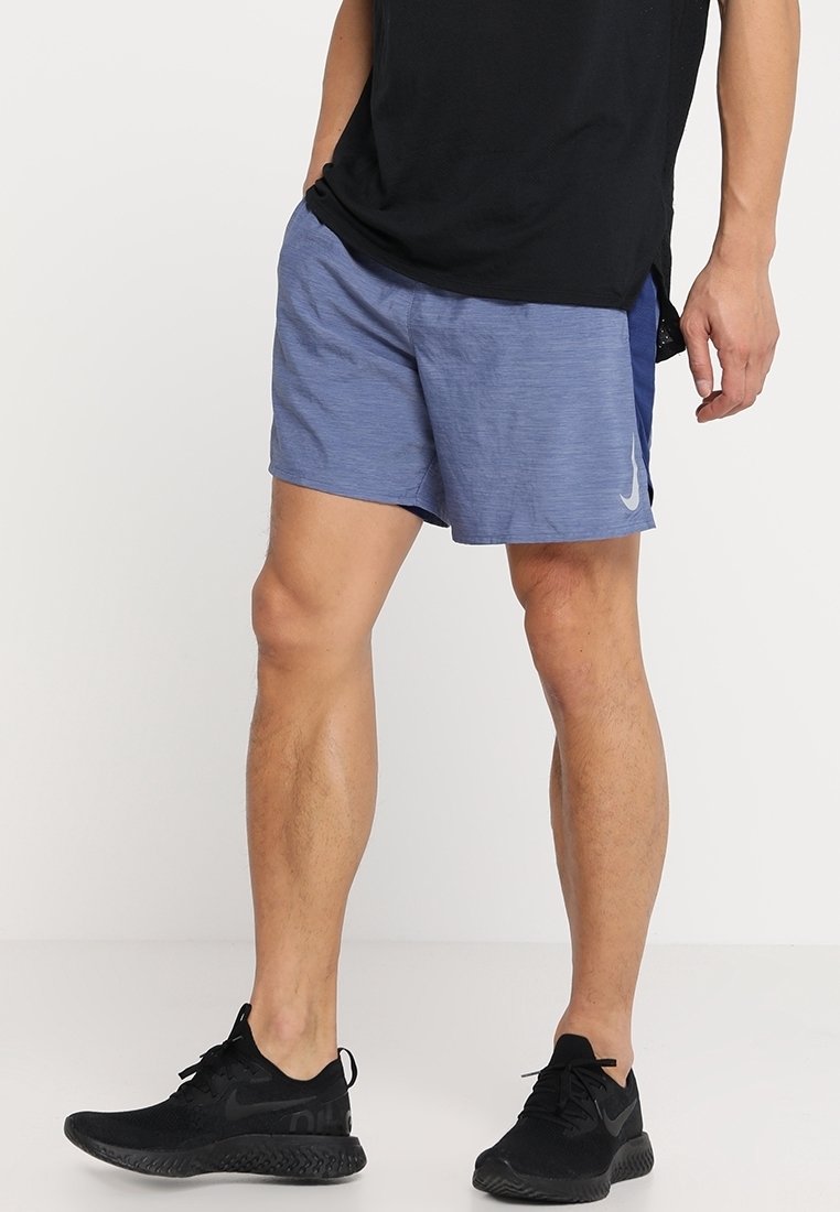 Blå atletiska shorts för män i lättviktsmaterial, med en texturerad yta och en vit logotyp på sidan. I kombination med svarta sneakers.