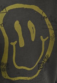 Design con impronta gialla a mano con una farfalla e piccolo testo scritto a mano in nero su sfondo di tessuto scuro.