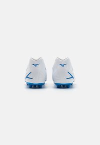Botas de fútbol con una parte superior sintética blanca lisa, acentos en azul, diseño de tacón curvado y tacos cónicos en una suela azul.