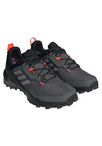 Czarno-szare buty do biegania po szlakach z teksturowanym materiałem, pomarańczowymi akcentami, czarnymi sznurówkami oraz wytrzymałą podeszwą zapewniającą przyczepność.