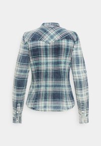 Chemise à carreaux bleue et verte à manches longues avec poignets boutonnés vue de dos sur un fond blanc uni.