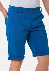 Blaue Baumwollshorts mit geradem Schnitt, umgeschlagenen Säumen, roten Nähten und Fronttaschen. Verfügt über einen Knopfverschluss und Gürtelschlaufen.