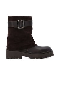 Brązowy zamszowy botek za kostkę z błyszczącym brązowym skórzanym czubkiem i grubą gumową podeszwą. Posiada szeroki czarny pasek z kwadratową metalową klamrą.