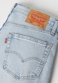 Ανοιχτό μπλε τζιν Levi's διπλωμένο για να φαίνεται η πίσω τσέπη, η κόκκινη ετικέτα Levi's και το δερμάτινο ταμπελάκι με το μέγεθος W32 L32.