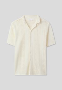 Camicetta a maniche corte di colore crema chiaro, realizzata in tessuto a maglia testurizzato con righe verticali e chiusura frontale con bottoni. Presenta un colletto morbido.