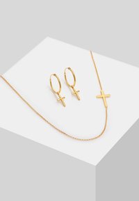 Goldfarbener Schmuckset bestehend aus einer zarten Kettenhalskette mit einem Kreuzanhänger und passenden Creolenohrringen mit kleinen Kreuzakzenten.