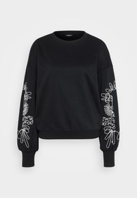 Svart crewneck genser med puffermer som har hvit, abstrakt linjeart broderi langs ytre armer og ribbestrikkede mansjetter.