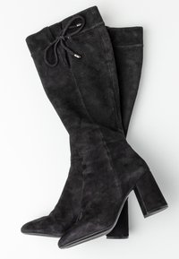 Mustat mokkasaappaat, joissa on korkea varsi, terävät kärjet, tukevat korot ja nyörit ylhäällä, kuvattu valkoista taustaa vasten.