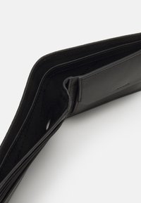 Portafoglio in pelle nera dal design elegante, con più scomparti per carte e una texture liscia; esposto parzialmente aperto su uno sfondo bianco.
