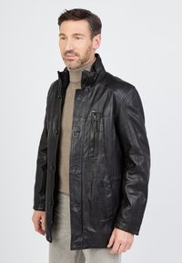 Schwarze Lederjacke mit hohem Kragen, Knopfverschluss und einer Reißverschlusstasche auf der Brust. Sie verfügt über eine glatte Textur und eine taillierte Passform.