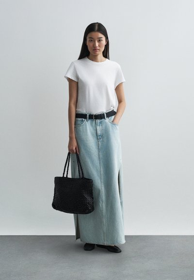 Άσπρη κοντομάνικη μπλούζα, ψηλόμεση ανοιχτό μπλε τζιν φούστα maxi με πλαϊνές σχισμές, μαύρη ζώνη και υφασμάτινη μαύρη τσάντα tote. Μαύρες μπαλαρίνες.