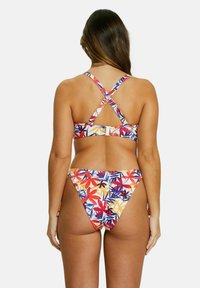 Bikini multicolore avec un imprimé floral en rouge, jaune et bleu. Le haut a des bretelles croisées et une fermeture à clip dans le dos.