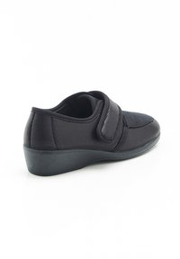 Scarpe nere realizzate in rete e materiale sintetico con una fascia in velcro, forma arrotondata, tacco basso e superficie superiore testurizzata.