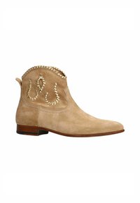 Beige suède enkelboot met een puntige neus, decoratieve gouden accenten en een golvende bovenkant. Beschikt over een lage gestapelde hak.