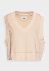 Top sin mangas color beige con escote en forma de V, hecho de una tela suave, que presenta un dobladillo acanalado y detalles en los costados. Etiqueta visible en la costura lateral.