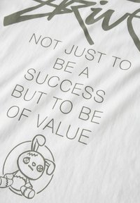 Biała bawełniana koszulka z ciemnoszarym napisem: "NIE TYLKO BYĆ SUKCESEM, ALE BYĆ WARTOŚCIĄ" oraz grafiką przeszywanego króliczka.