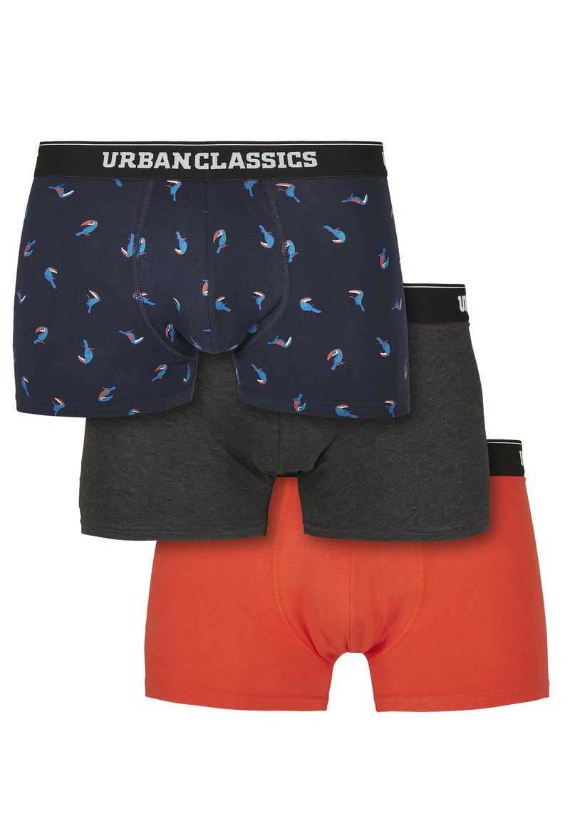 Drei Paare Boxershorts: eine marineblaue mit einem sich wiederholenden Vogelmuster, eine dunkelgraue und eine leuchtend orange; alle mit schwarzen Markenbundleisten.