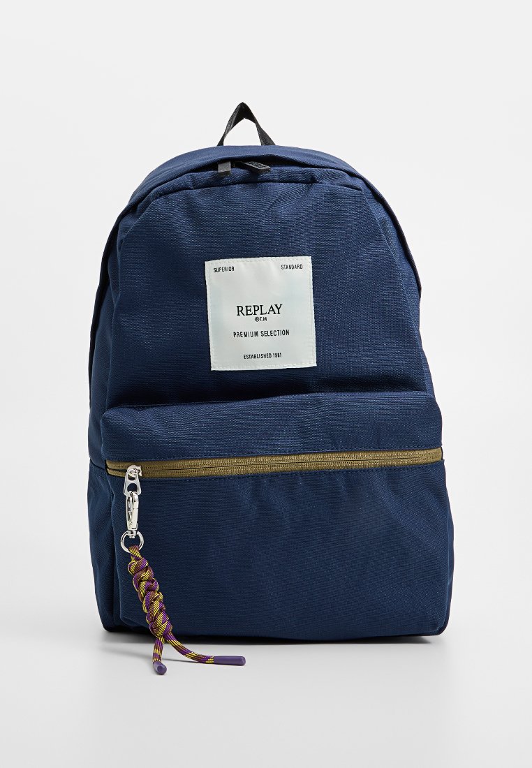 Zaino blu navy realizzato in tessuto strutturato, con una tasca anteriore con cerniera in oro, un tirazip intrecciato e un'etichetta del marchio bianca.