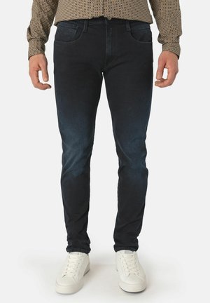 Mørke denim skinny jeans med en glatt tekstur, med fem lommer og subtile falming detaljer, sammen med hvite joggesko.